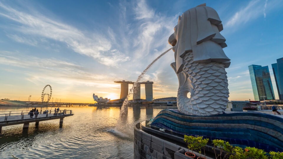 Iconic Merlion statue and Marina Bay Sands skyline in Singapore at sunset.