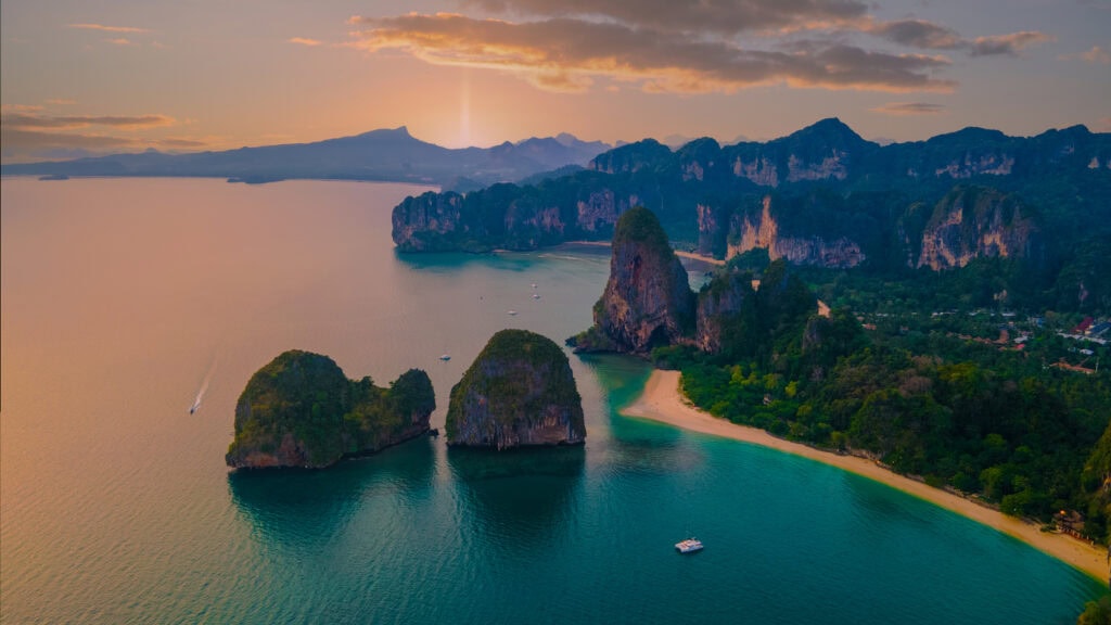 Limestone cliffs by serene ocean sunset.