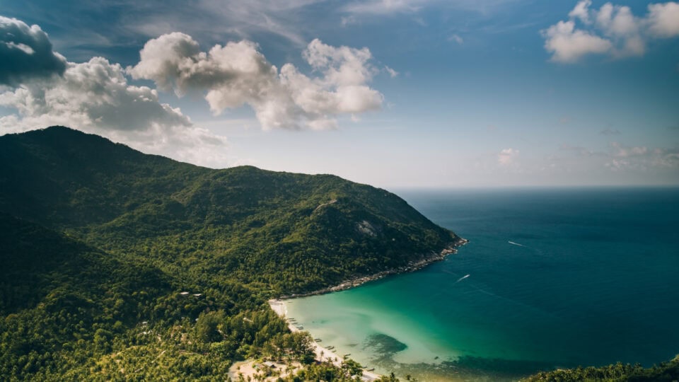 Scenic beach view with lush mountains.