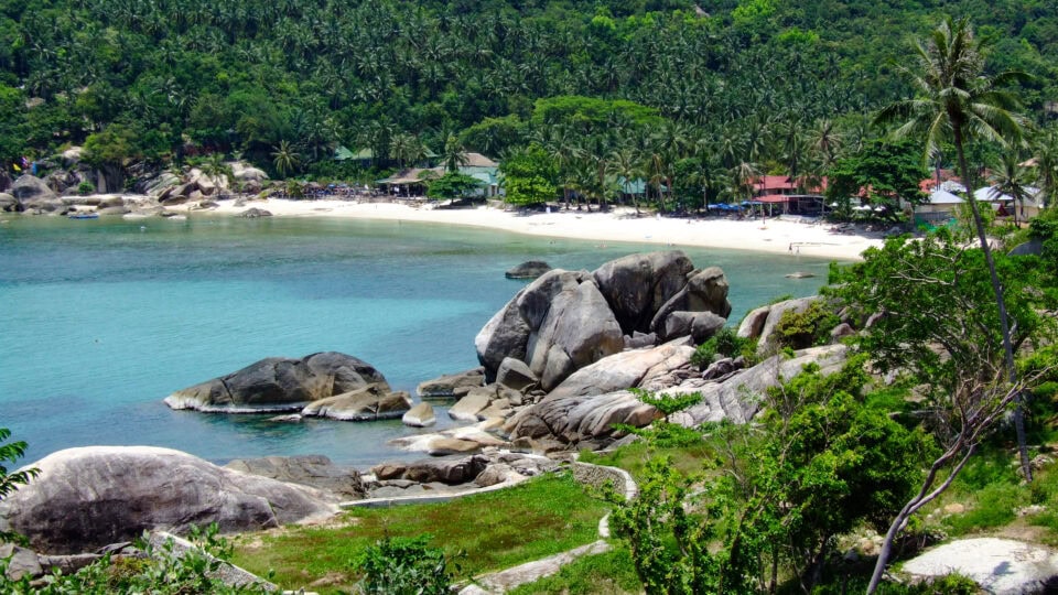 Tropical beach with rocks and greenery.