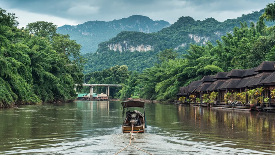 Boat on tranquil river surrounded by greenery.