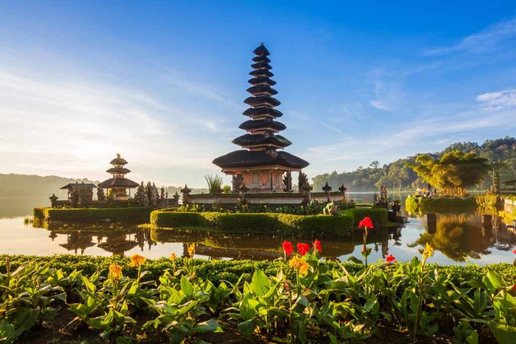 Serene temple surrounded by water and flowers.