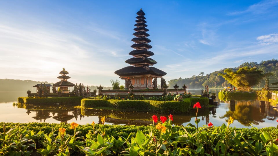 Serene temple surrounded by water and flowers.