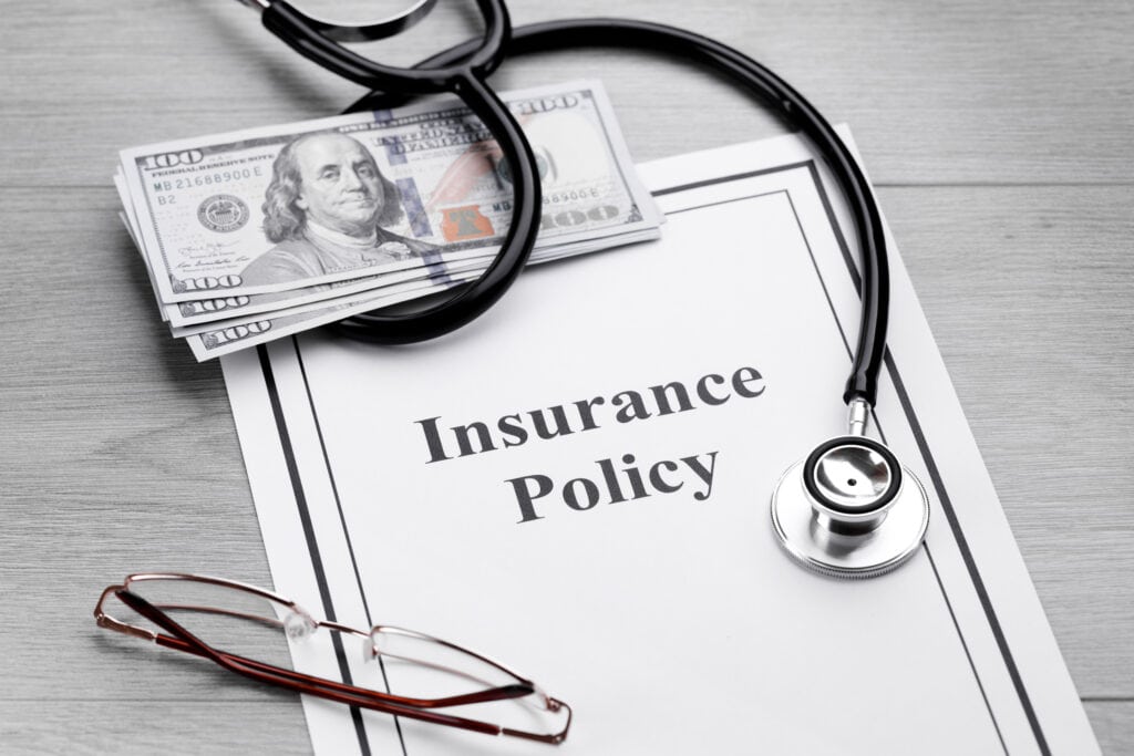 Insurance policy with money and stethoscope
