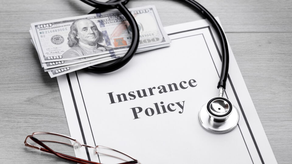 Insurance policy with money and stethoscope