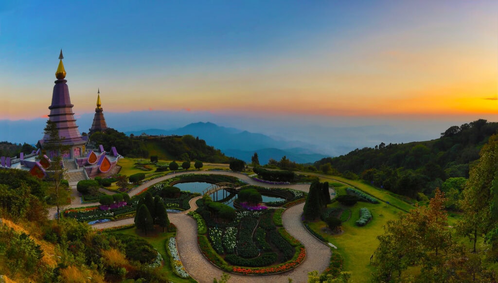 Pagodas amidst lush mountains at sunset.