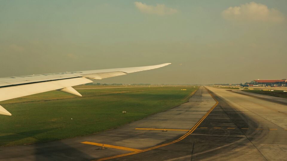 Airplane wing over runway landscape