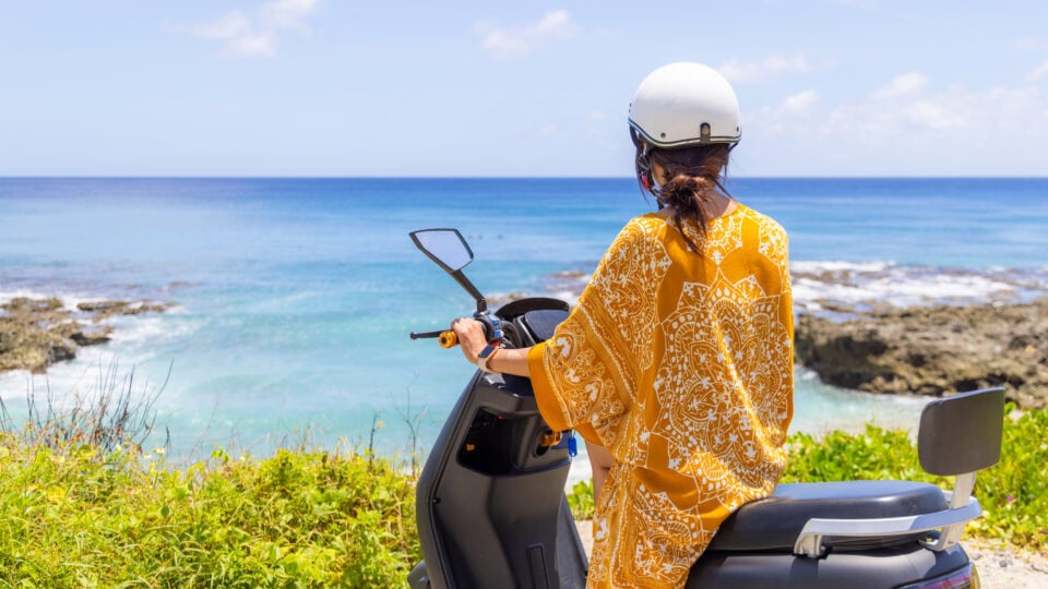 Woman on scooter by the sea.