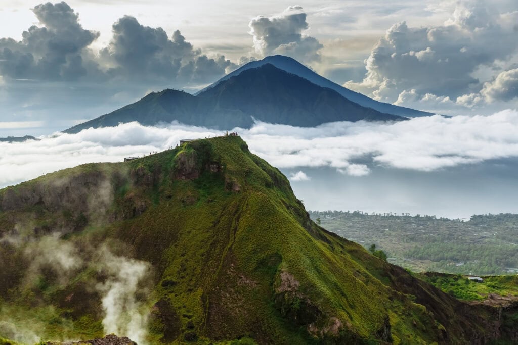 Lush green volcano amidst clouds.