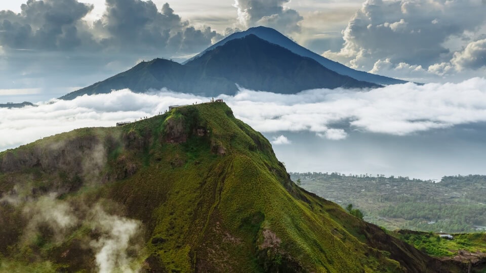 Lush green volcano amidst clouds.