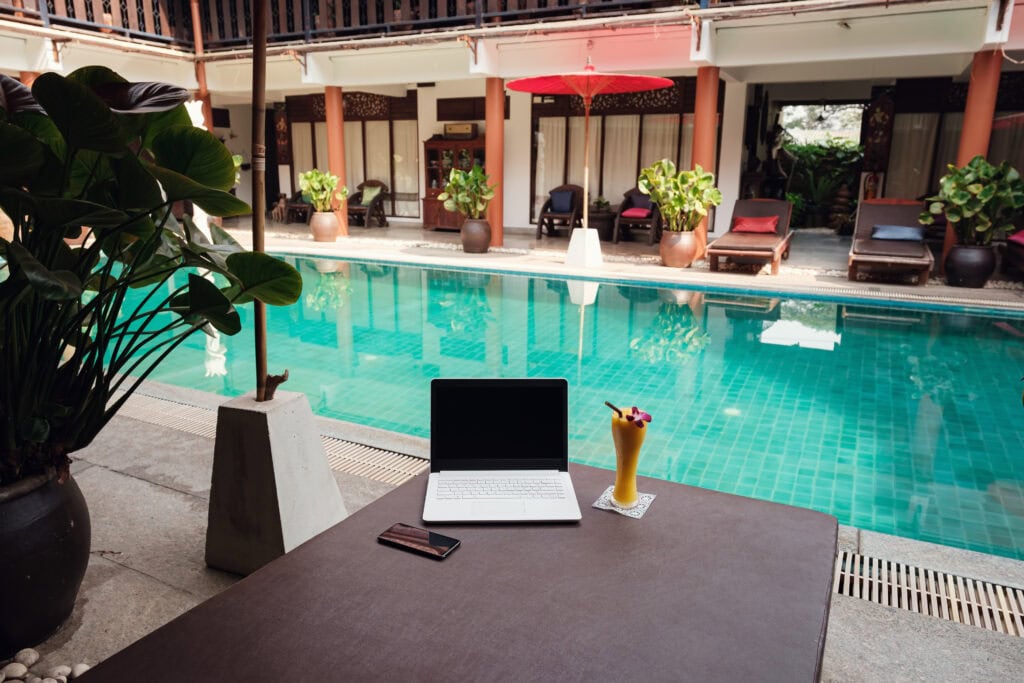 Laptop and drink by poolside