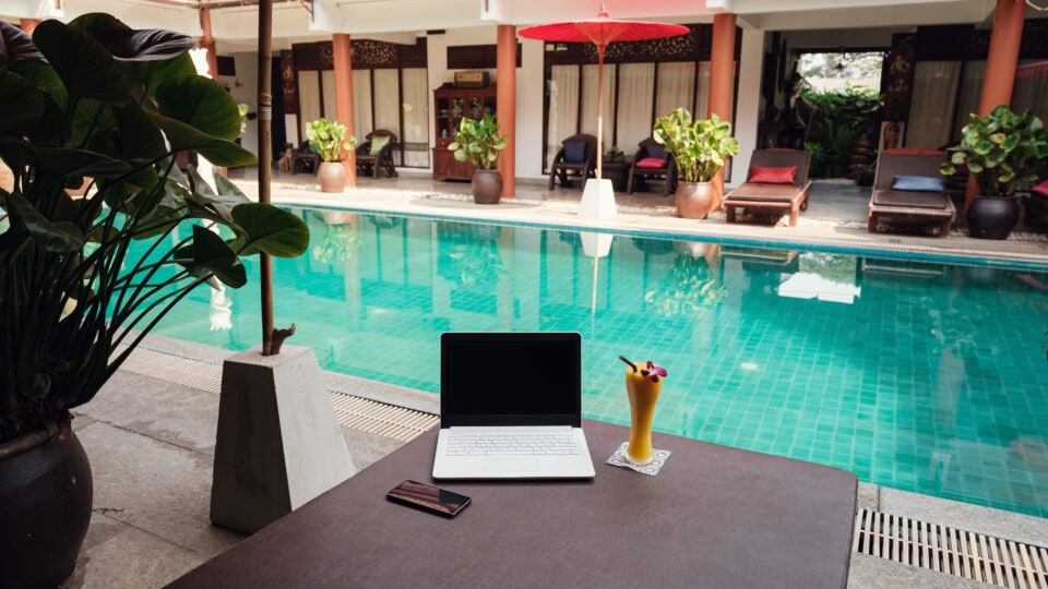 Laptop and drink by poolside
