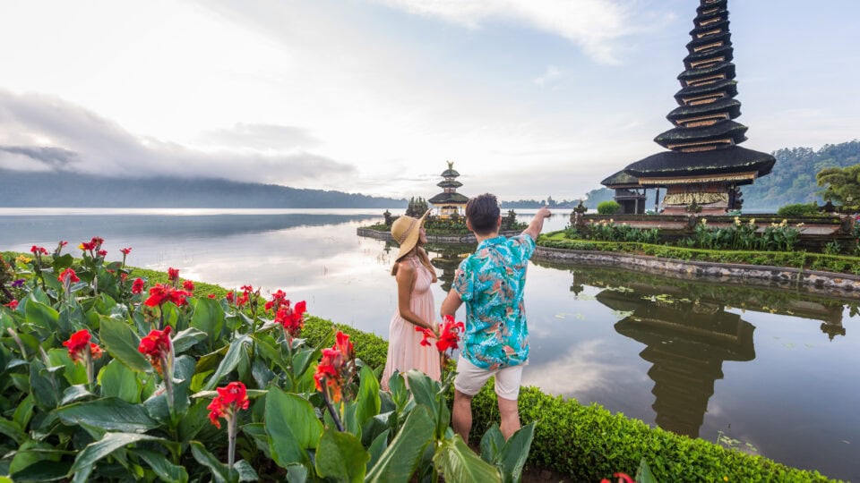 Couple admiring temple by lake.