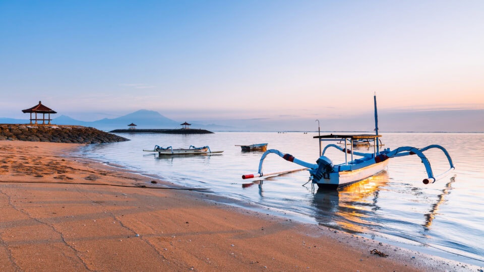 Calm beach with fishing boats at sunrise.