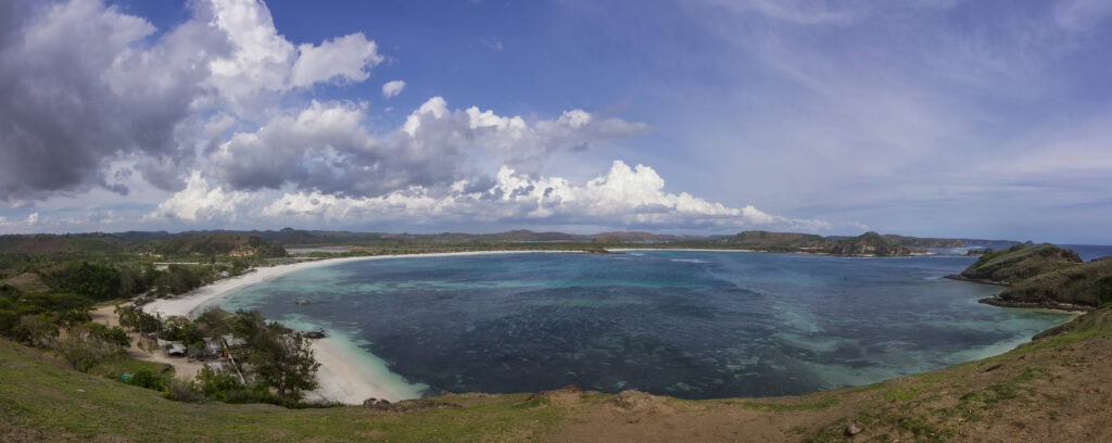 Scenic beach with turquoise waters and clouds.