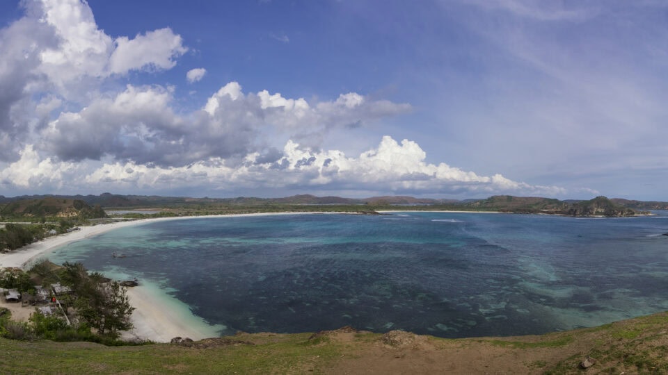 Scenic beach with turquoise waters and clouds.