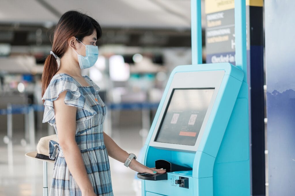 Woman using check-in kiosk at airport.