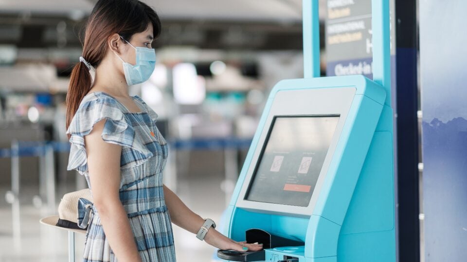 Woman using check-in kiosk at airport.