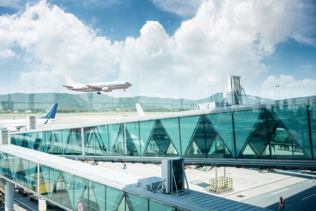 Airplane landing near modern terminal.