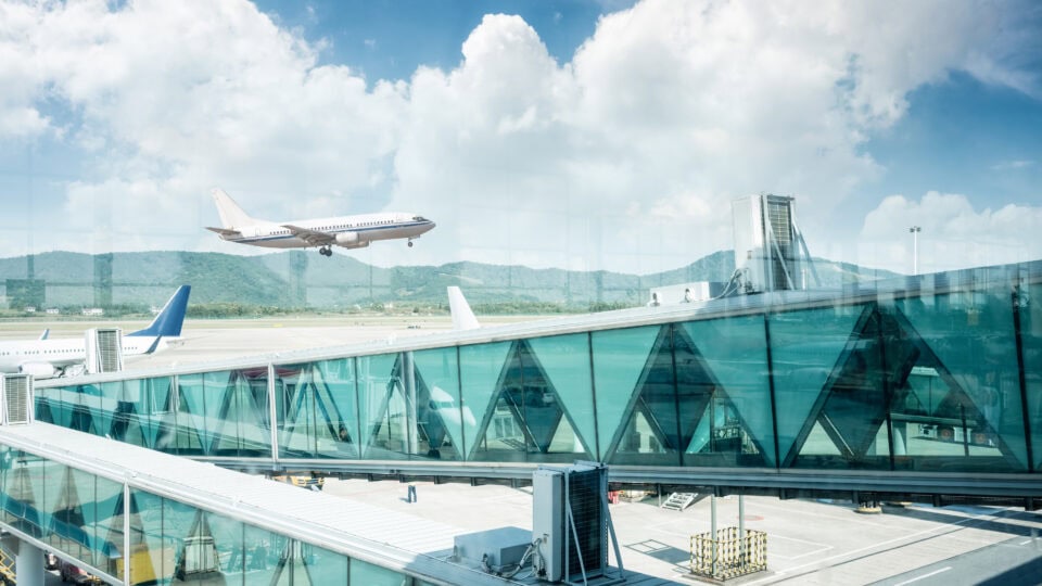 Airplane landing near modern terminal.