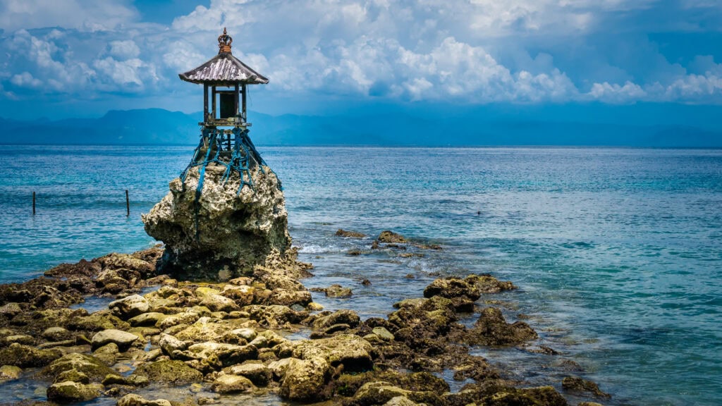 Lone structure on rocky shoreline.