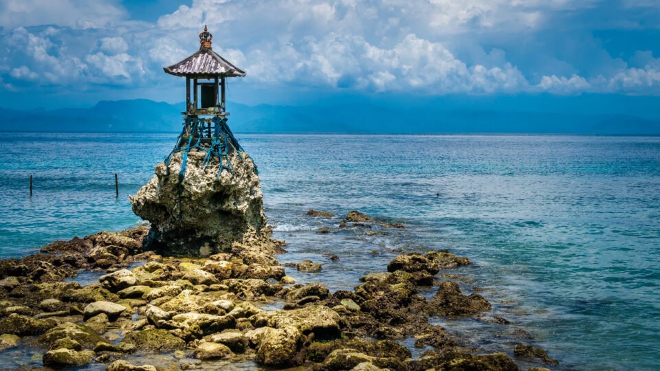 Lone structure on rocky shoreline.