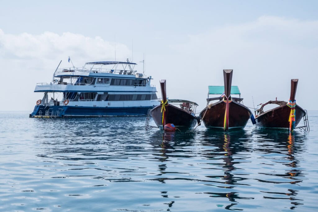 Three boats near a ferry ship.