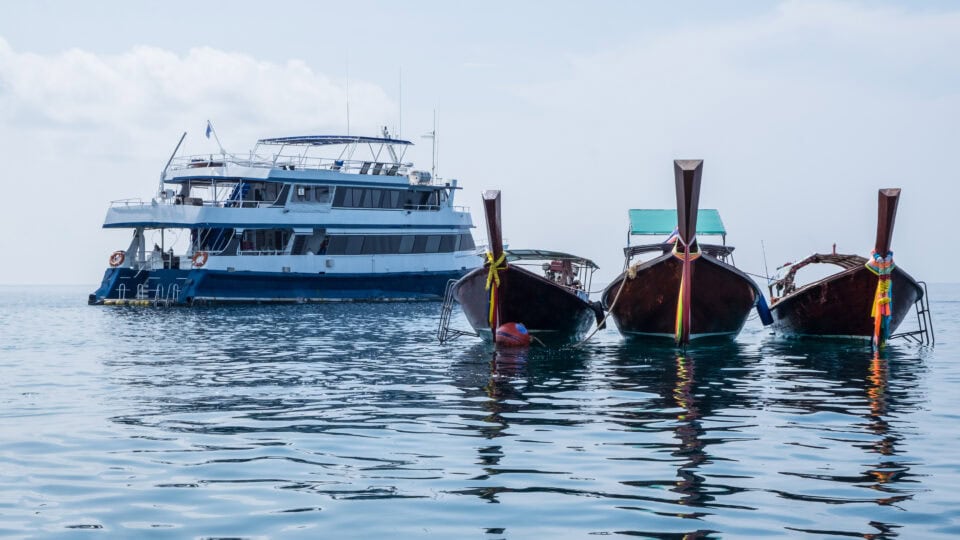 Three boats near a ferry ship.