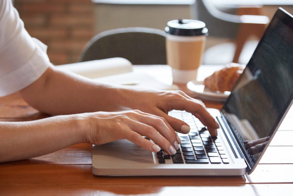 Person typing with coffee and croissant