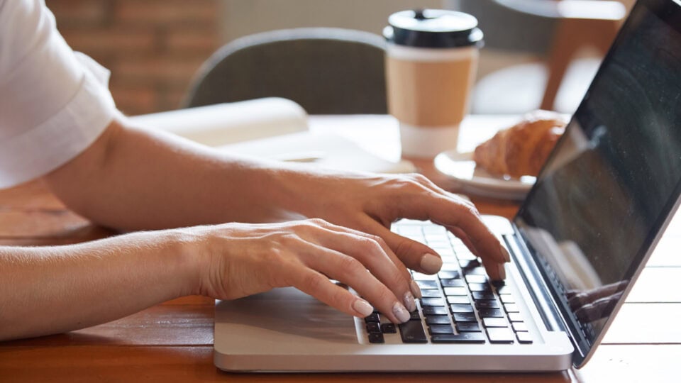 Person typing with coffee and croissant
