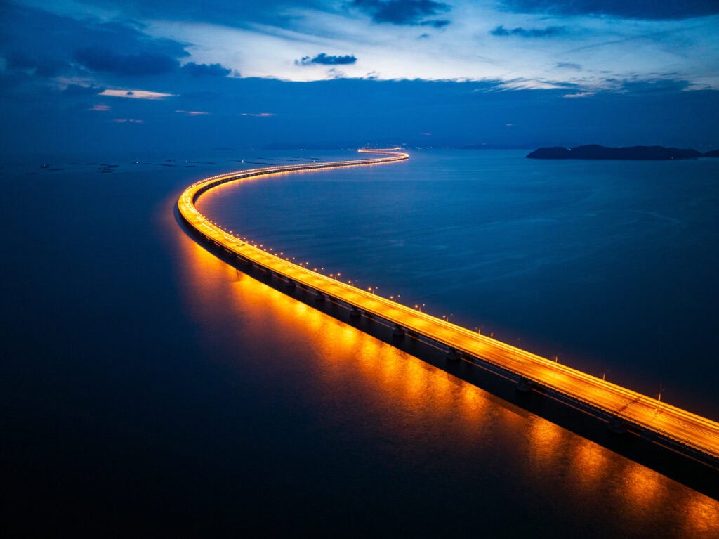 Illuminated bridge over calm water.