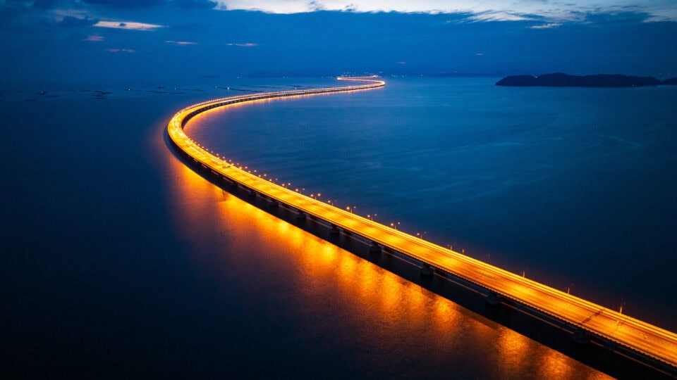 Illuminated bridge over calm water.