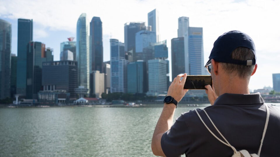 Tourist photographing Singapore skyline.